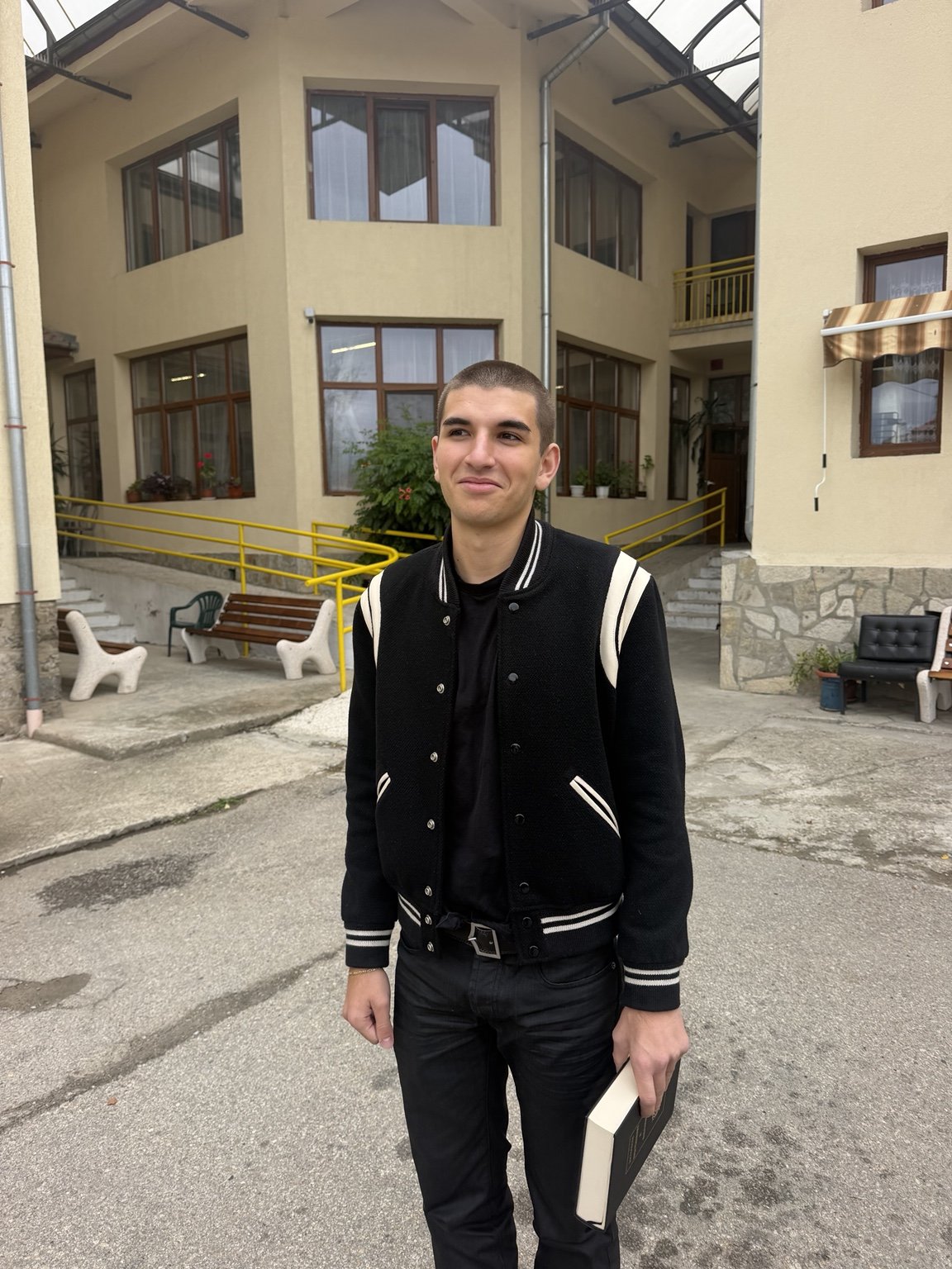 Vladislav outside the residential home in Samokov, holding a book
