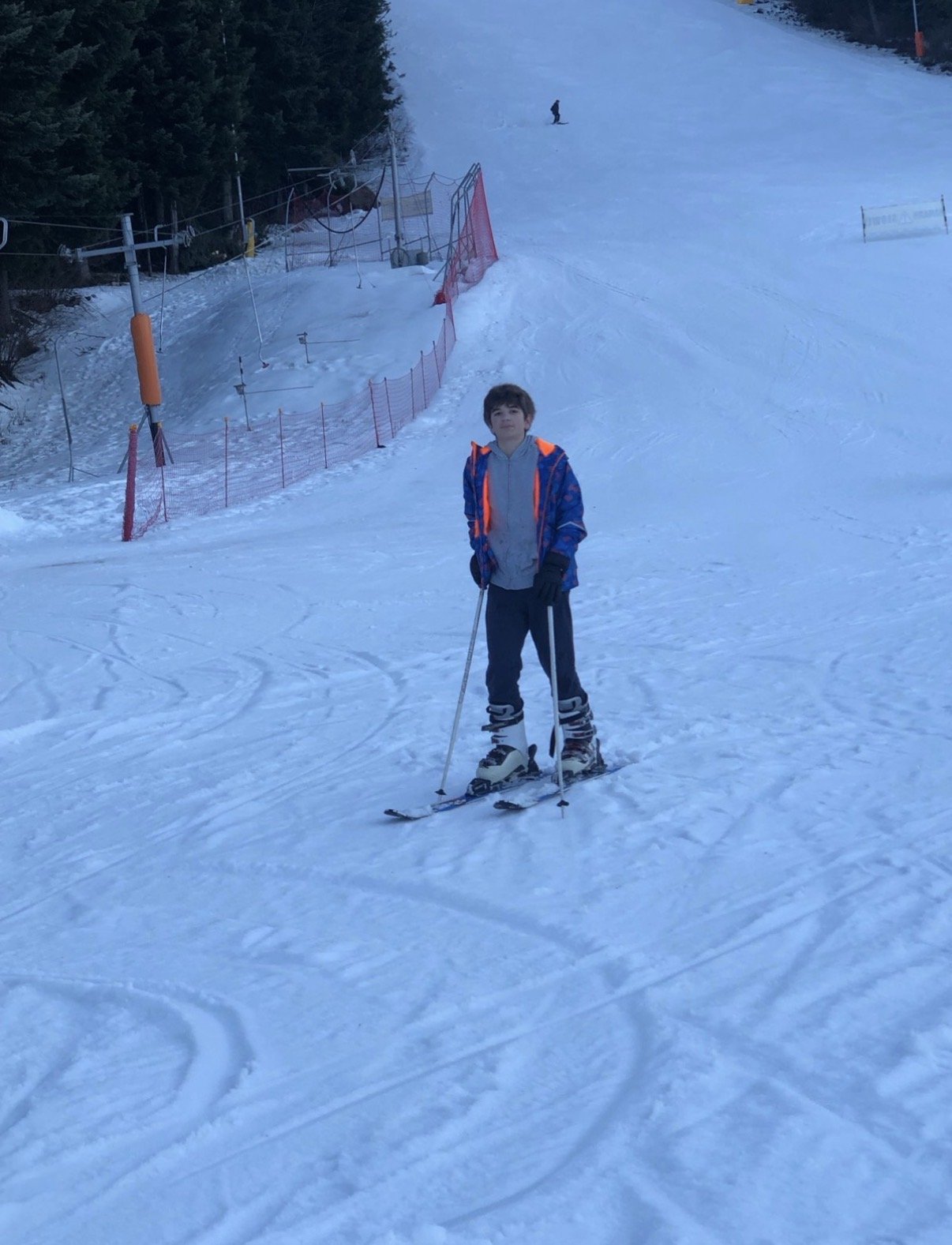 A young Vladislav standing on a ski slope with skis and poles